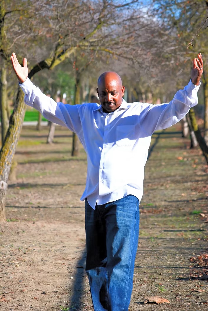 Arthur Jae with arms raised in a park